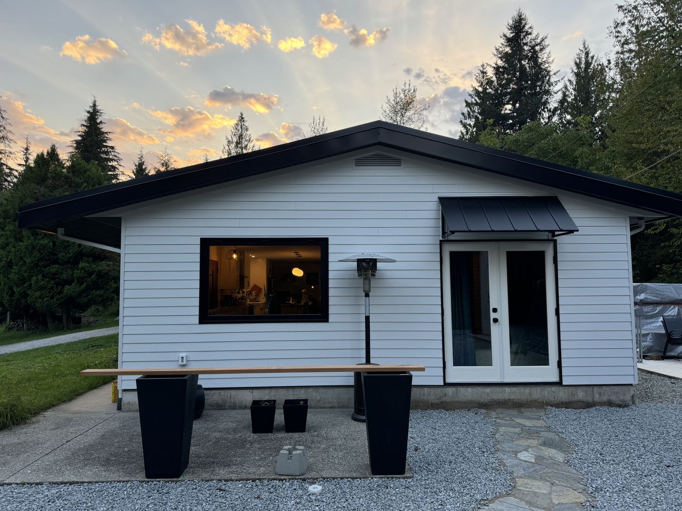 White-sided modern cabin with black trim and French doors at sunset