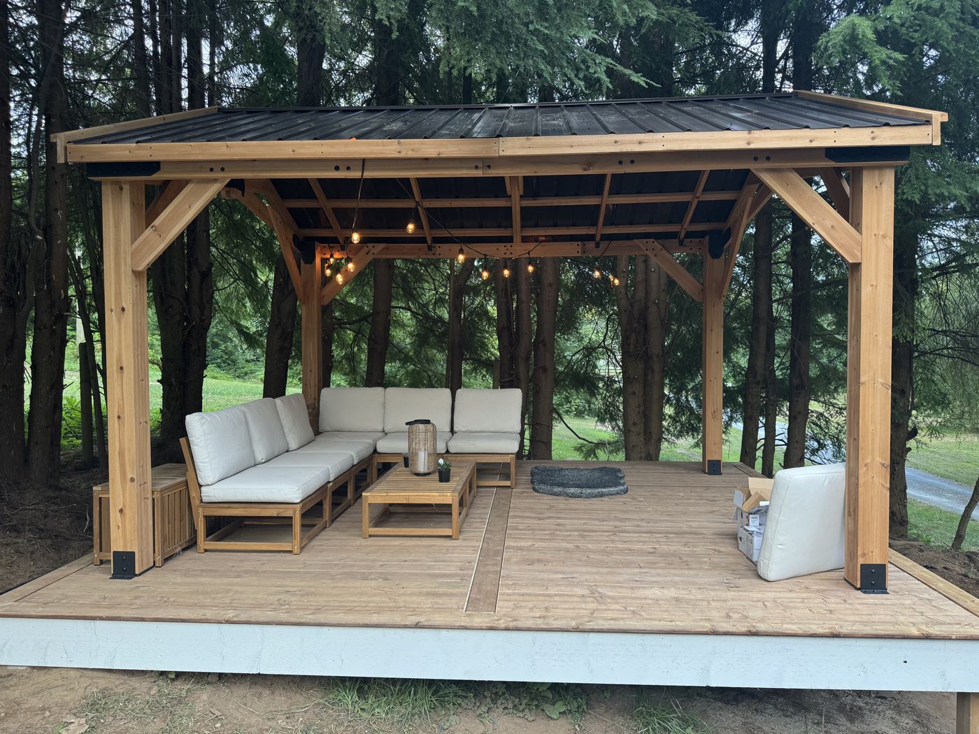 Cedar pavilion with metal roof and outdoor sofa on a wood deck