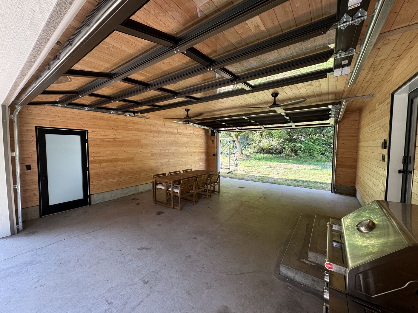 Covered cedar-lined patio with glass garage door and dining table