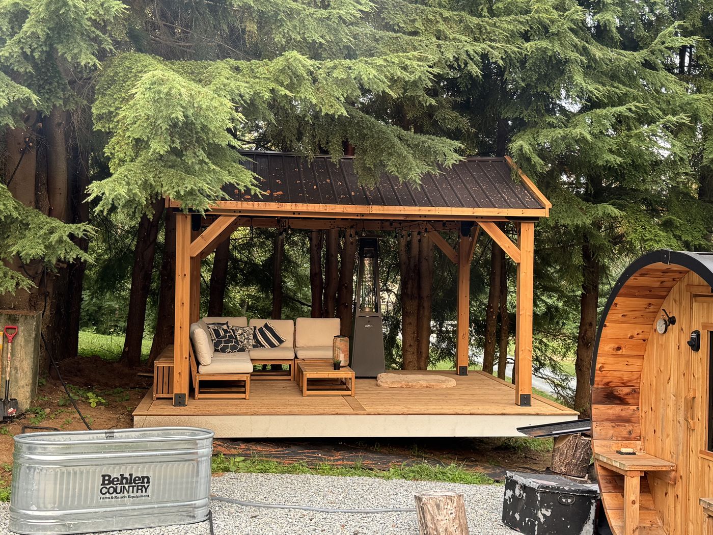 Timber pavilion lounge with sectional seating beside a barrel sauna